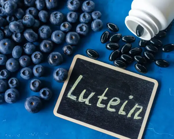 Jagody i kapsułki z luteiną na oczy. Na tabliczce napis "Lutein".
