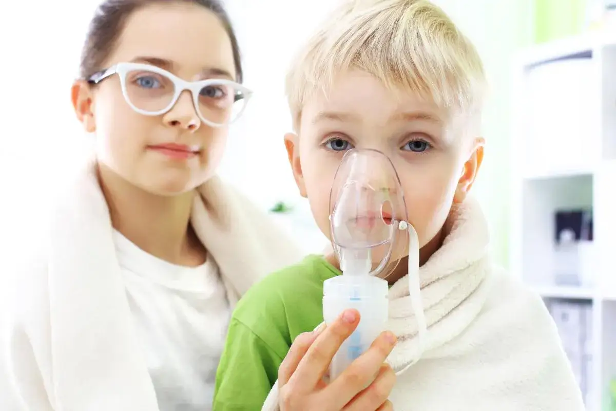 Dziecko z maską inhalacyjną, siostra obok. Ile dni można robić inhalacje z soli fizjologicznej? Zapytaj lekarza.